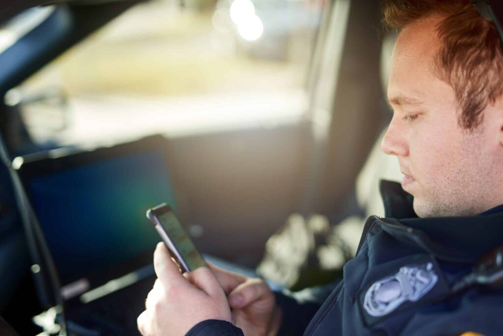 Police,,Officer,And,Man,Texting,With,Phone,In,Patrol,Car